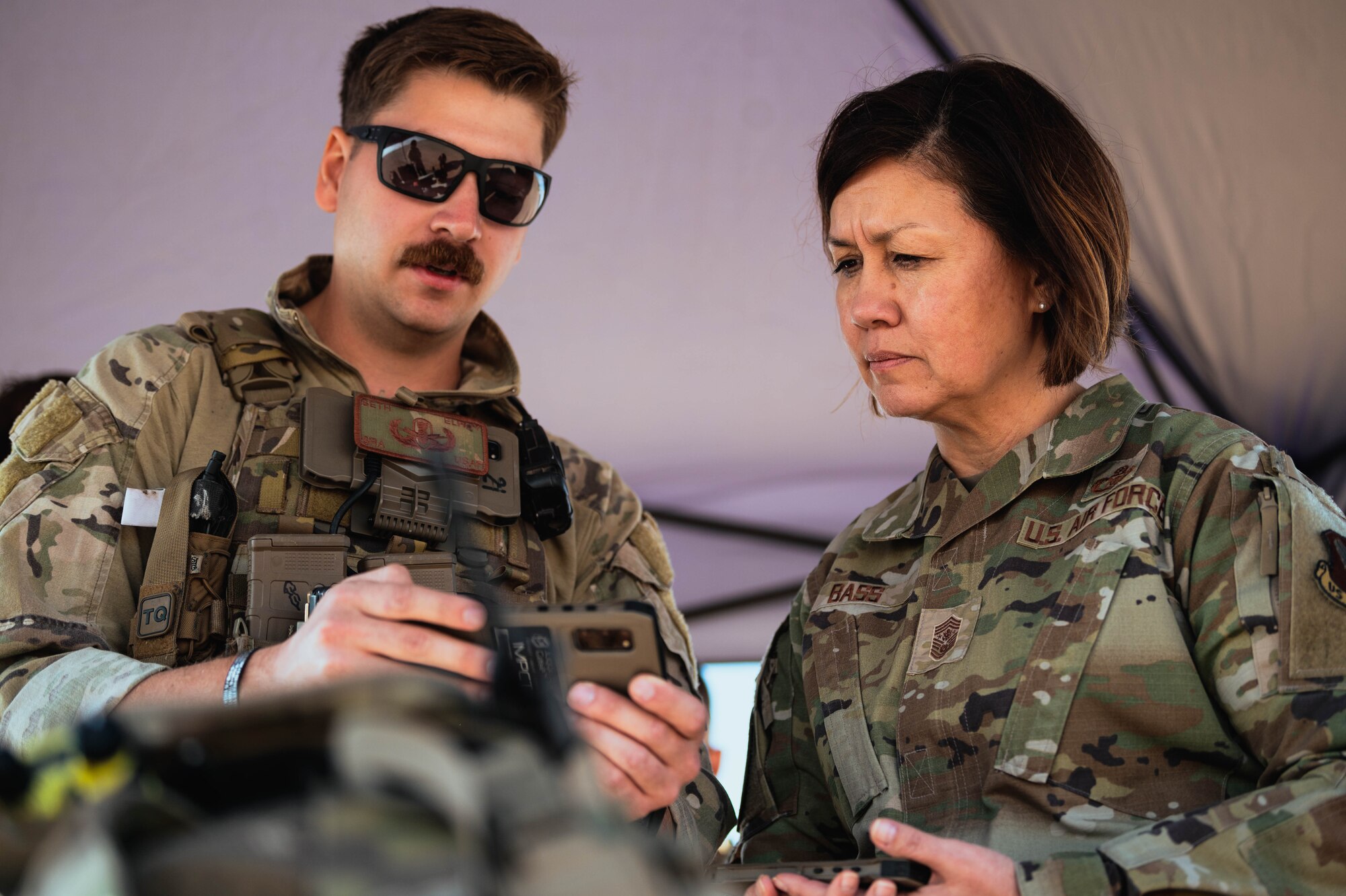 Chief Master Sgt. of the Air Force Joanne Bass (right), and an EOD technician from the 56th Civil Engineer Squadron (left) view Android Team Awareness Kit (ATAK) technology during her base tour