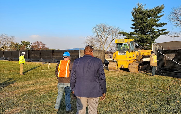 over the shoulder of people watching a bulldozer move dirt