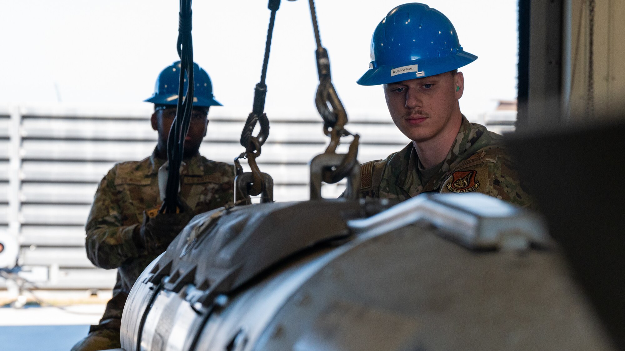 Airman 1st Class Jerad Leathem, right, and Airman 1st Class Khaliq Gilmore, 8th Maintenance Squadron conventional maintenance crew technicians, position a guided bomb unit-31 version 3 on a building rack