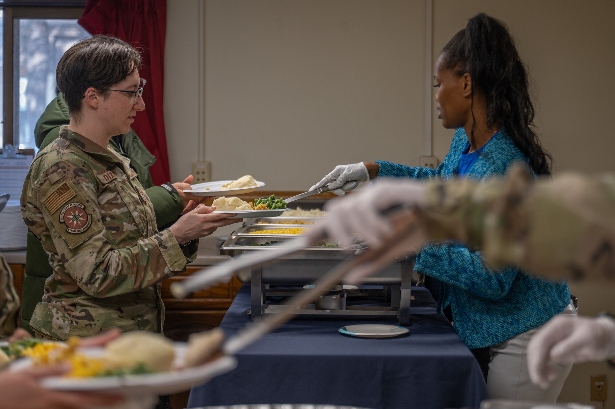 Senior Airman Lauren Dixon, left, 8th Operational Medical Readiness Squadron medical technician, receives a plate of food from Tech. Sgt. Michelle Young, USO Osan volunteer.