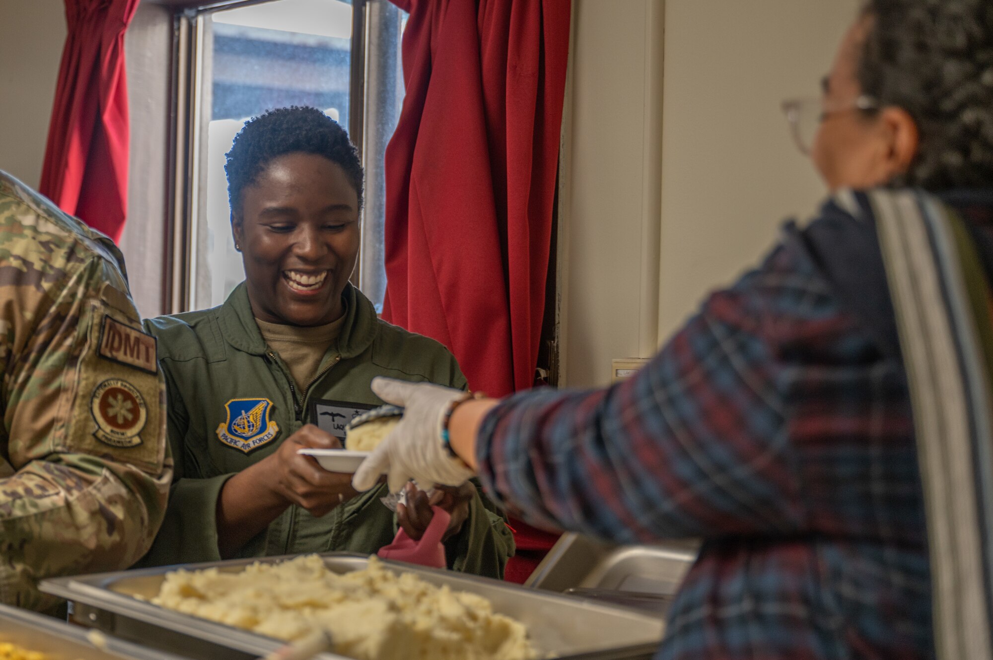 Maj. LaQuita Moore, 8th Operational Medical Readiness Squadron aerospace medicine nurse practitioner, receives a plate of food from a USO Osan volunteer