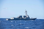 The Arleigh Burke-class guided missile destroyer USS Thomas Hudner (DDG 116) steams alongside the Ticonderoga-class guided missile cruiser USS Normandy (CG 60) while both ships are underway as part of the Ford Carrier Strike Group, March 15, 2023.