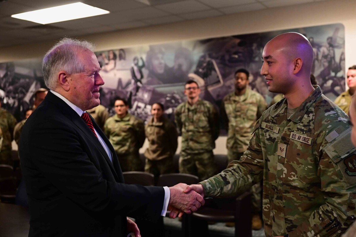 Secretary of the Air Force Frank Kendall presents a challenge coin to Staff Sgt. Frank McCall, 31st Medical Group Airman, before a mission brief.