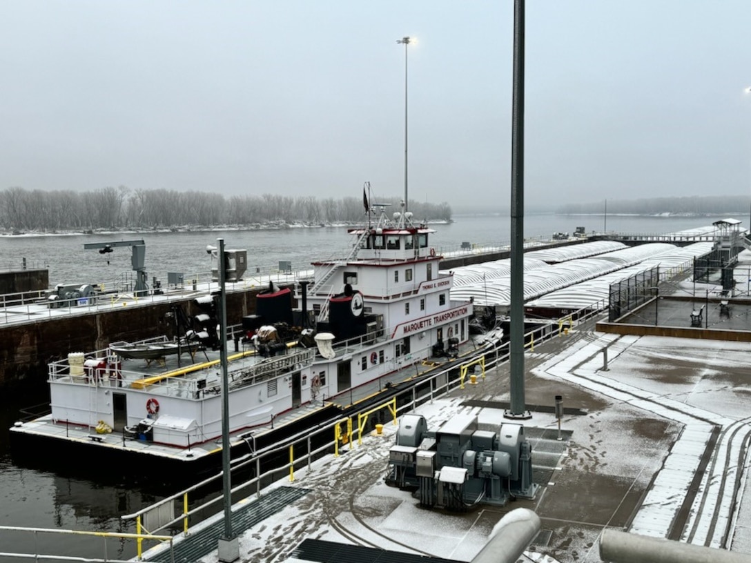 big boat in the water pushing many boxes down a river.