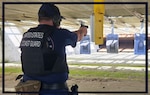 A coast guard member is in body armor at a firing range with his weapon level and pointed at the targets during a qualification course.