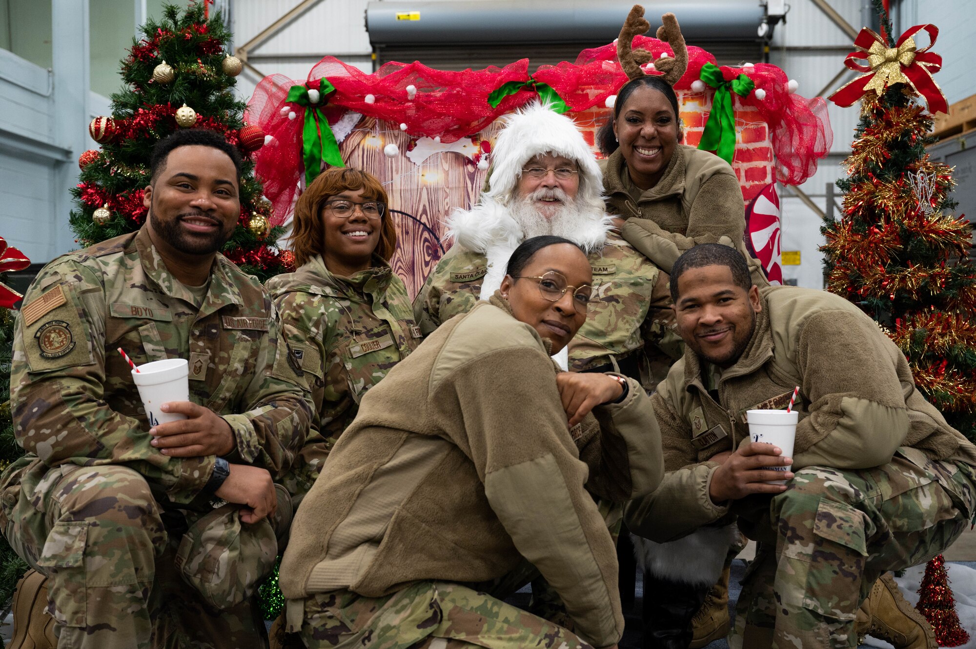Uniformed Airmen pose for a picture with Santa Claus during the children’s Christmas party.