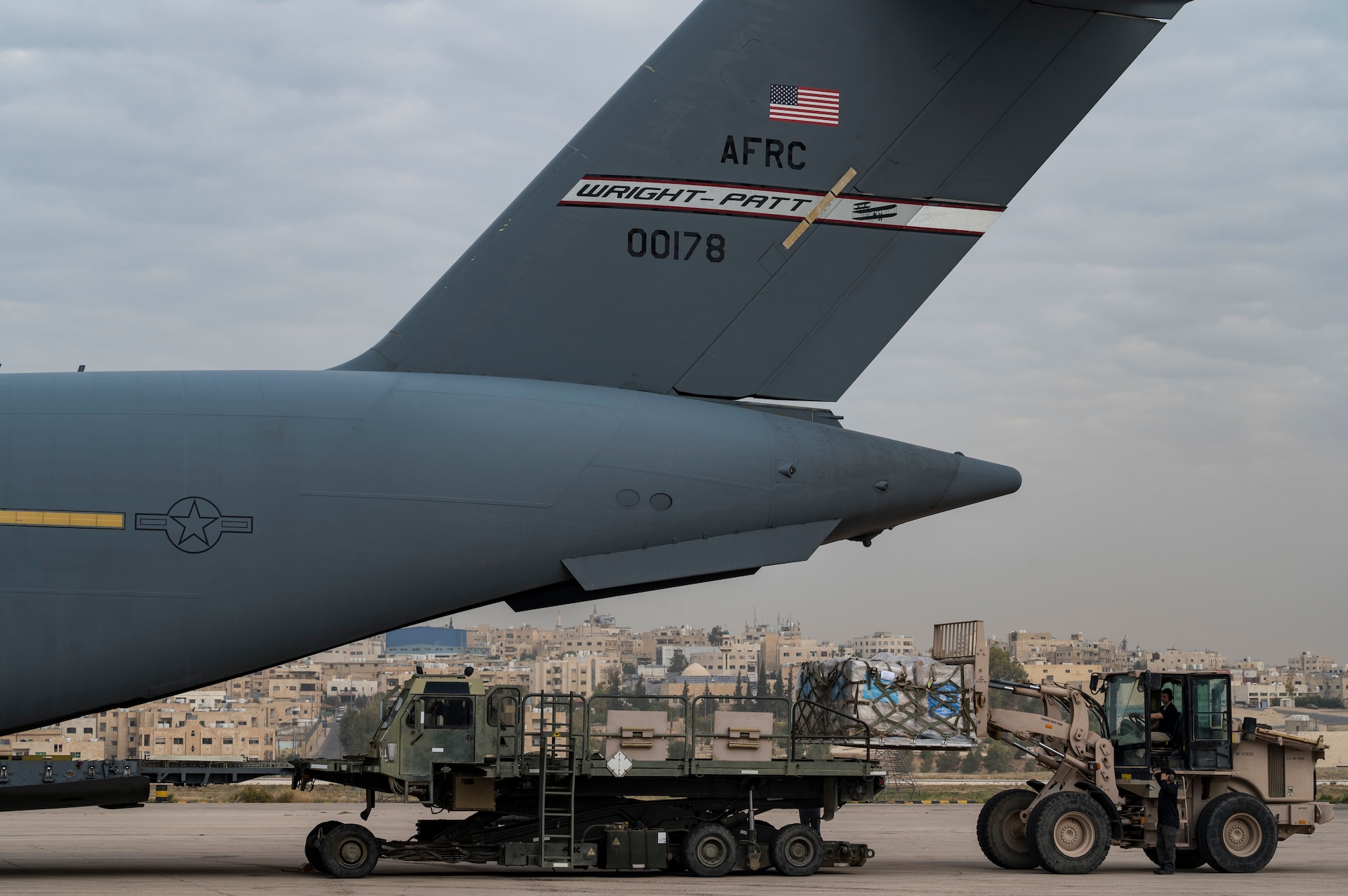 Airmen and USAID personnel load humanitarian aid onto a C-17.