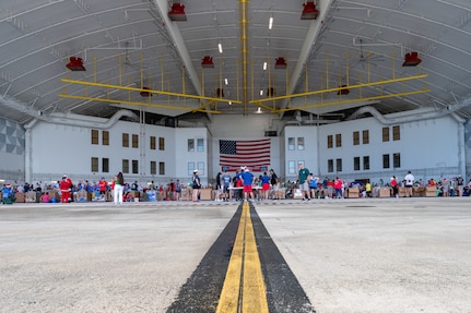 Volunteers and members of the U.S. Air Force, Japan Air Self-Defense Force, Royal Canadian Air Force, Republic of Korea Air Force, and Royal Australian Air Force decorate boxes during the annual bundle building event in support of Operation Christmas Drop 2023 (OCD 23) at Andersen Air Force Base, Guam, Dec. 2, 2023. The tradition began during the Christmas season in 1952 when a B-29 Superfortress aircrew saw islanders waving at them from the island of Kapingamarangi, 3,500 miles southwest of Hawaii. In the spirit of Christmas, the aircrew dropped a bundle of supplies attached to a parachute to the islanders below, giving the operation its name. Today, airdrop operations include more than 50 islands throughout the Pacific. (U.S. Air Force photo by Senior Airman Brooklyn Golightly)