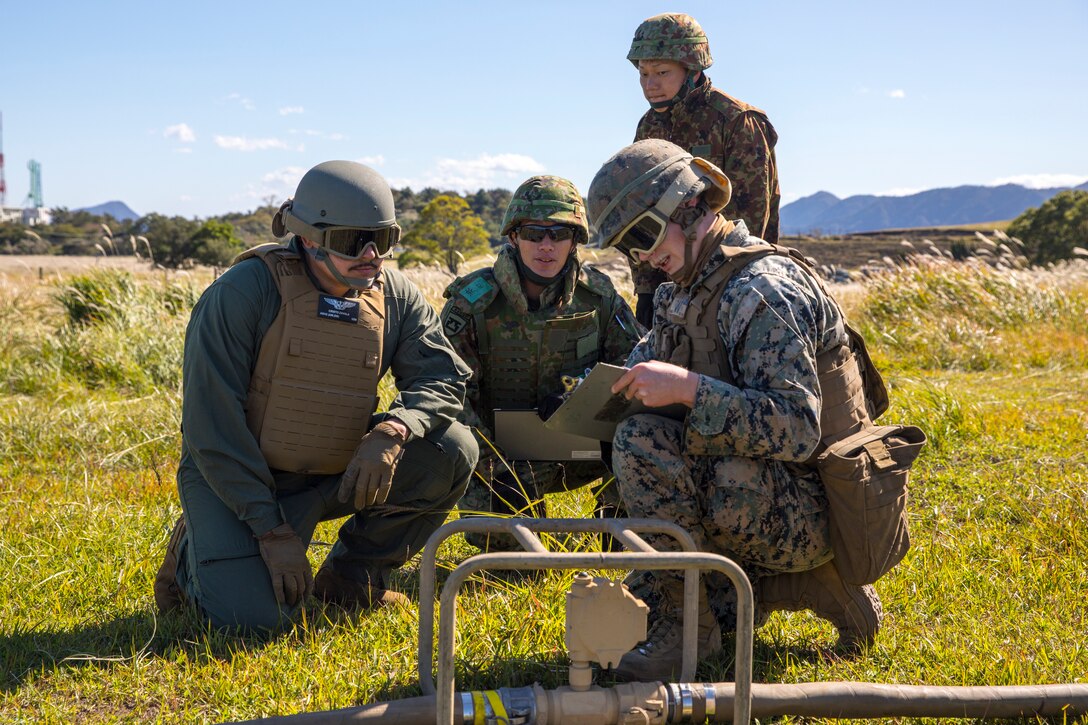 U.S. Marines with Marine Wing Support Squadron 171, Sailors with Navy Cargo Handling Battalion 1, Naval Weapons Station Yorktown, and Japan Ground Self-Defense Force (JGSDF) service members with 1st Battalion, Western Army Helicopter Unit, Western Army Aviation Group, discuss the use of a fuel meter while participating in the field training exercise portion of Resolute Dragon 23 at JGSDF Camp Jumonjibaru, Japan, Oct. 21, 2023. RD 23 is an annual bilateral exercise in Japan that strengthens the command, control, and multi-domain maneuver capabilities of Marines in III Marine Expeditionary Force and allied Japan Self-Defense Force personnel. (U.S. Marine Corps photo by Cpl. Chloe Johnson)