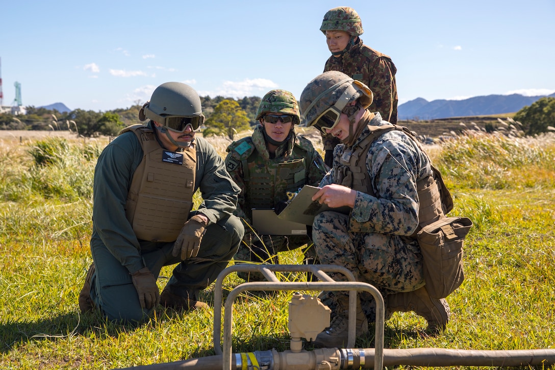 U.S. Marines with Marine Wing Support Squadron 171, Sailors with Navy Cargo Handling Battalion 1, Naval Weapons Station Yorktown, and Japan Ground Self-Defense Force (JGSDF) service members with 1st Battalion, Western Army Helicopter Unit, Western Army Aviation Group, discuss the use of a fuel meter while participating in the field training exercise portion of Resolute Dragon 23 at JGSDF Camp Jumonjibaru, Japan, Oct. 21, 2023. RD 23 is an annual bilateral exercise in Japan that strengthens the command, control, and multi-domain maneuver capabilities of Marines in III Marine Expeditionary Force and allied Japan Self-Defense Force personnel. (U.S. Marine Corps photo by Cpl. Chloe Johnson)