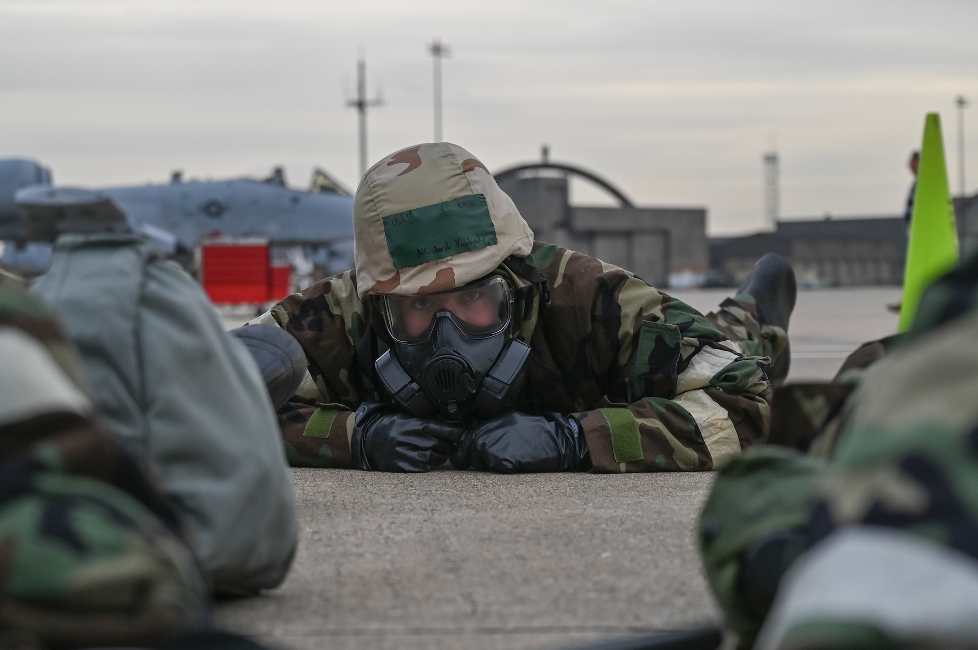 Maryland Air National Guard Airman 1st Class Jacob Kosubinsky, a crew chief assigned to the 175th Maintenance Squadron, takes cover wearing Mission-Oriented Protective Posture (MOPP) gear as the base is notified of a simulated incoming attack during Operation Frosty Strike Dec. 1, 2023, at Martin State Air National Guard Base, Middle River, Md.
