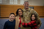 A soldier, his wife, and his two children pose for a family photo