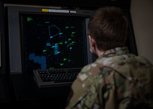Female looks at dark screen with green and blue aircraft markers