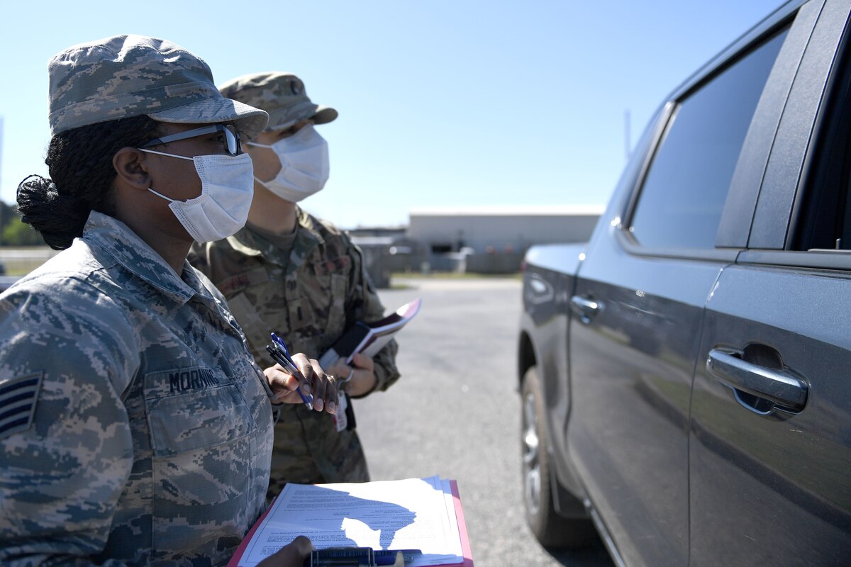 U.S. Air Force paralegal and assistant staff judge advocate assist Airmen with obtaining a power of attorney via a drive-thru legal assistance for deployers prior to their departure in order to continue physical distancing as part of COVID protection efforts. (U.S. Air Force photo by Senior Airman Kristine M. Gruwell)