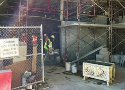 Men with safety vest on perform construction work in Orange and green safety vest. a metal frame work can be seen along with blocks.