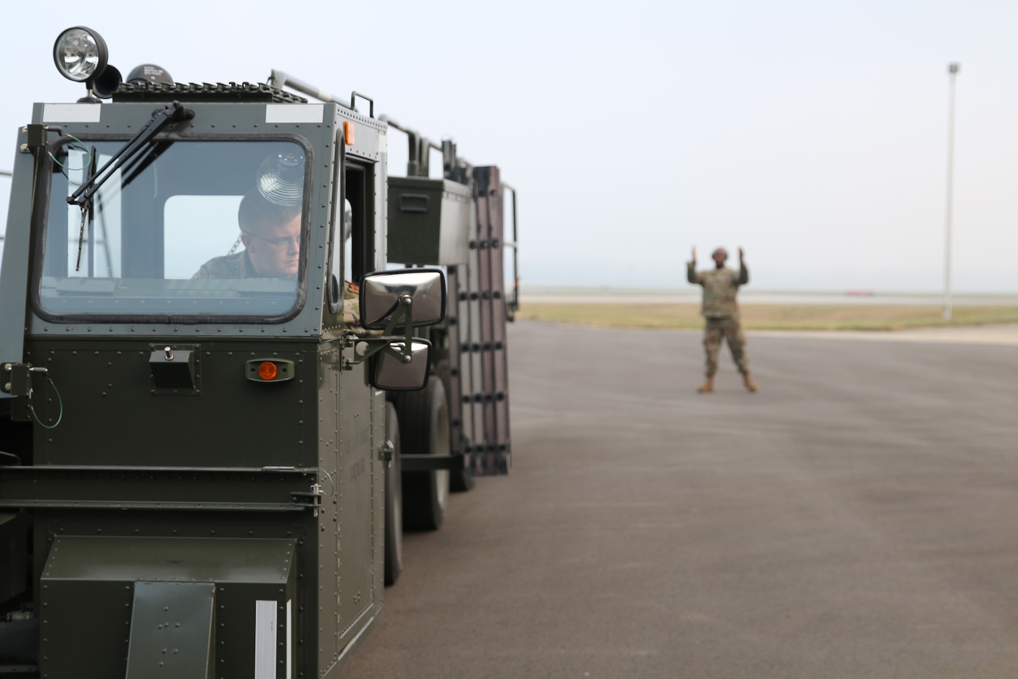 Staff Sgt. Bryce Phelps, passenger services representative, backs a 60K out of a parking bay at Wright-Patterson Air Force Base, Ohio, on Nov. 5, 2023, as Tech. Sgt. Dylan Lewis-Lee, ramp services agent, provides spotting signals. These loaders are used by ramp services agents in an aerial port to load and offload cargo pallets from various aircraft. Port Dawgs complete recertification training on vehicles periodically to ensure that they are deployment-ready to fill a role in any of the squadron’s duty sections.