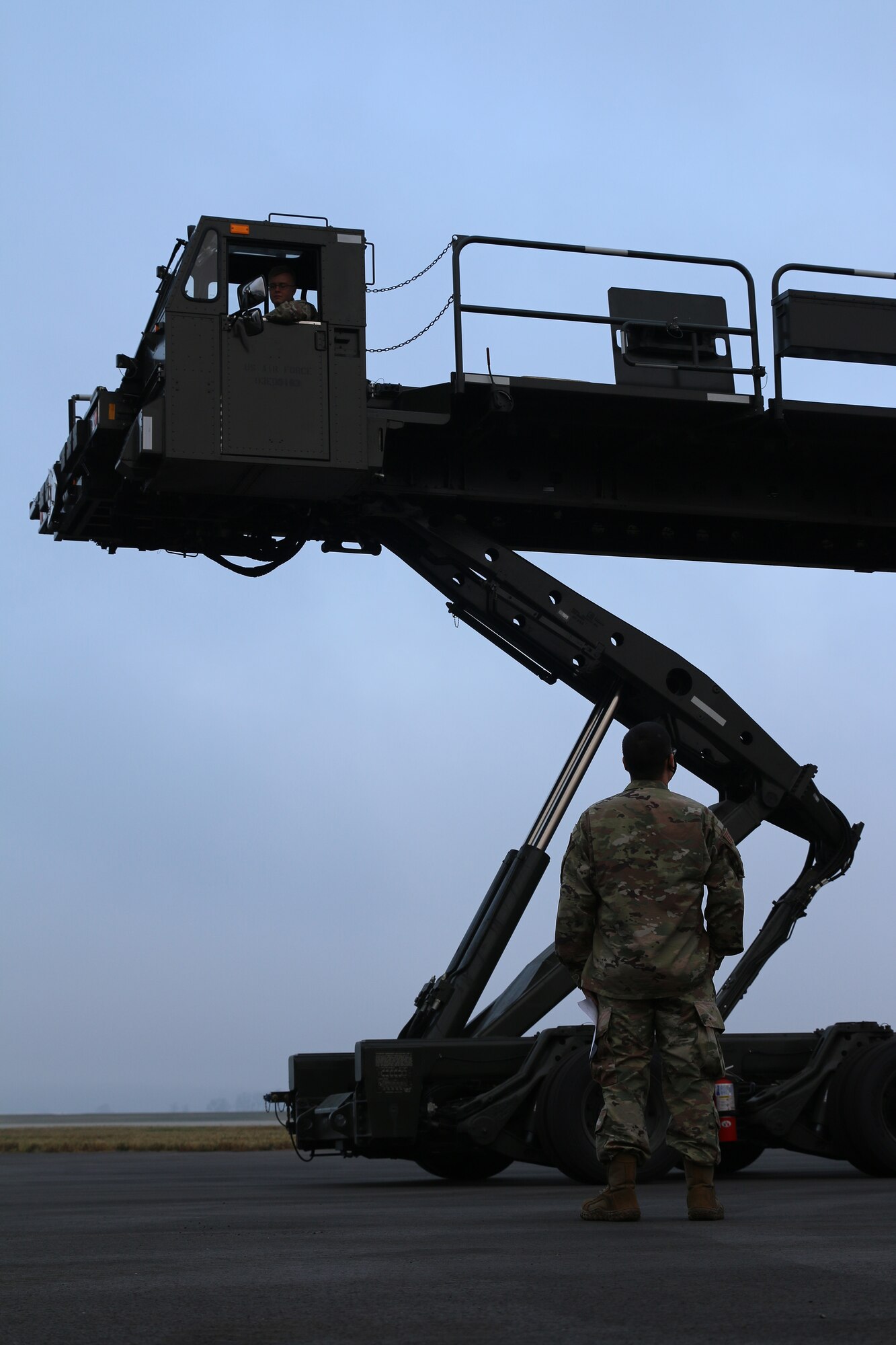 Tech. Sgt Kevin Shaffer, passenger services supervisor, coaches Staff Sgt. Bryce Phelps, passenger services representative, on raising the deck of a Tunner 60K loader, Nov. 5, 2023. These loaders are used by ramp services agents in an aerial port to load and offload cargo pallets from various aircraft. Port Dawgs complete recertification training on vehicles periodically to ensure that they are deployment-ready to fill a role in any of the squadron’s duty sections.