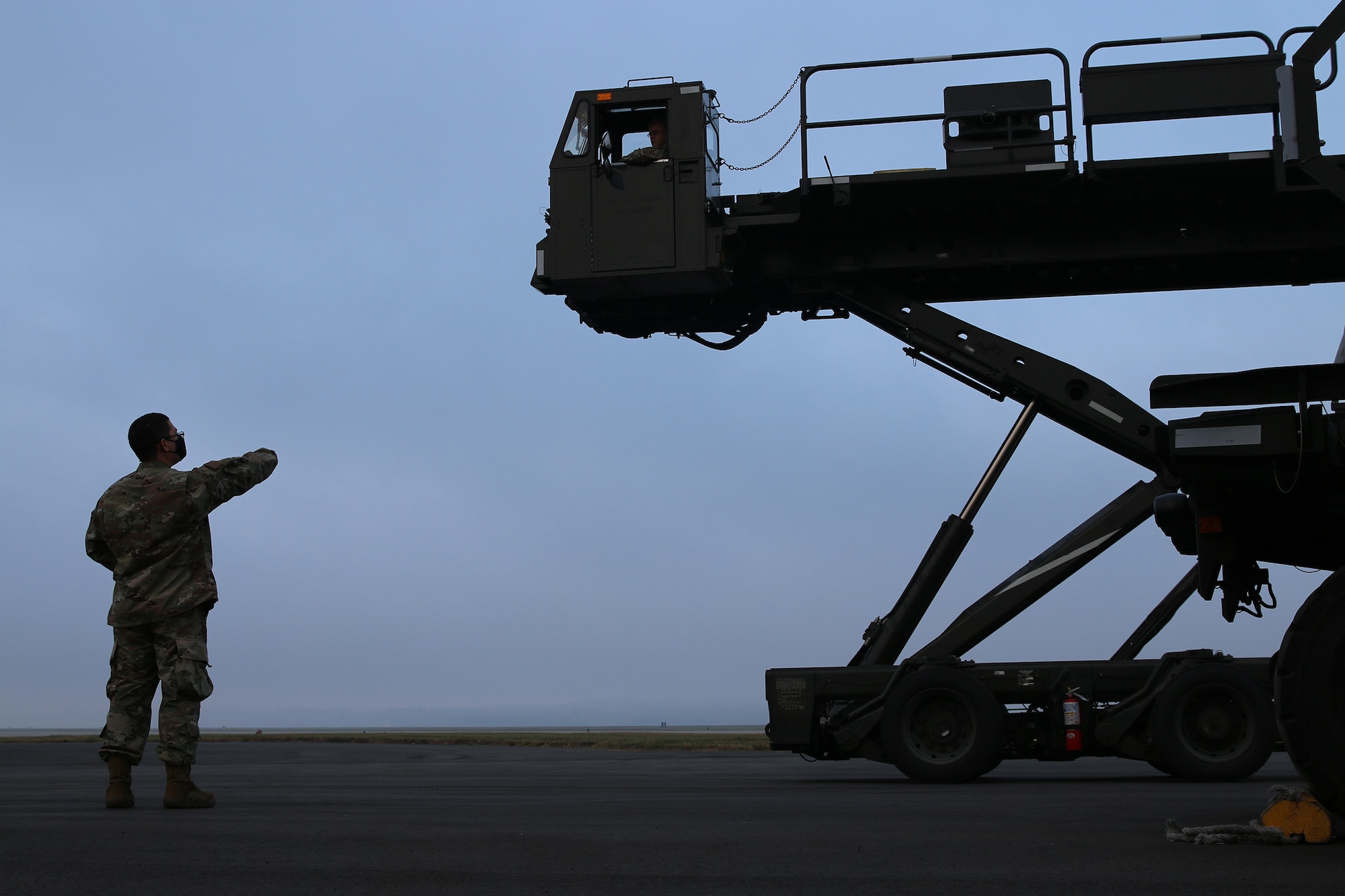 Tech. Sgt. Kevin Shaffer, passenger services supervisor, coaches Staff Sgt. Bryce Phelps, passenger services representative, on raising the deck of a Tunner 60K loader, Nov. 5, 2023. These loaders are used by ramp services agents in an aerial port to load and offload cargo pallets from various aircraft. Port Dawgs complete recertification training on vehicles periodically to ensure that they are deployment-ready to fill a role in any of the squadron’s duty sections.