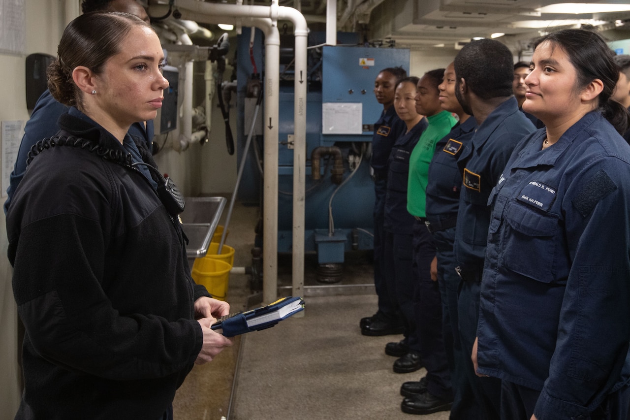 A sailor speaks to a large group of sailors.