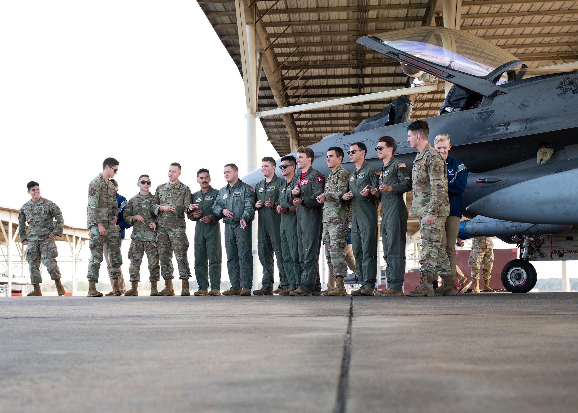 A group of cadets pose in front of an F-16 outside