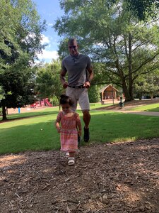 Staff Sgt. Marti stands under some trees with his daughter Isabella.