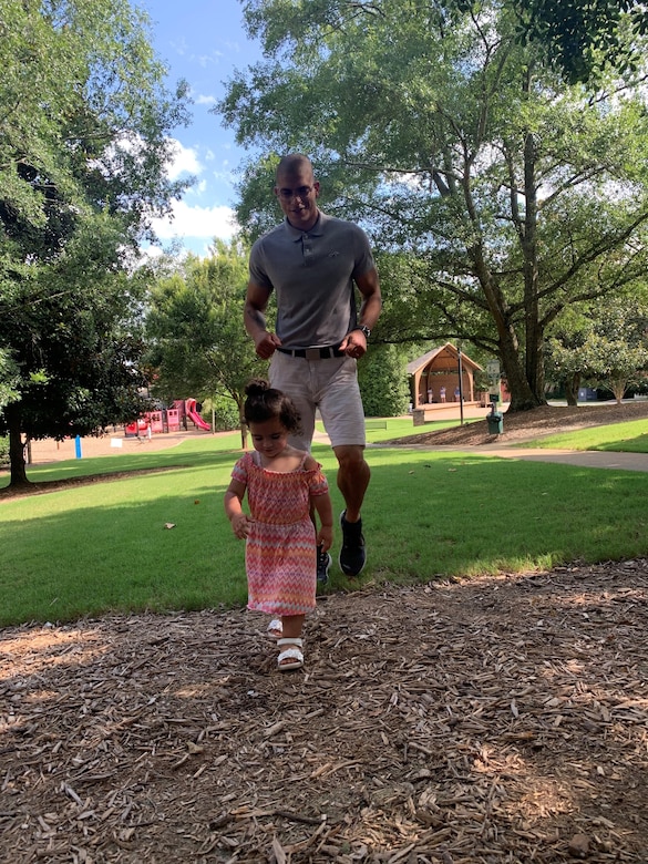 Staff Sgt. Marti stands under some trees with his daughter Isabella.