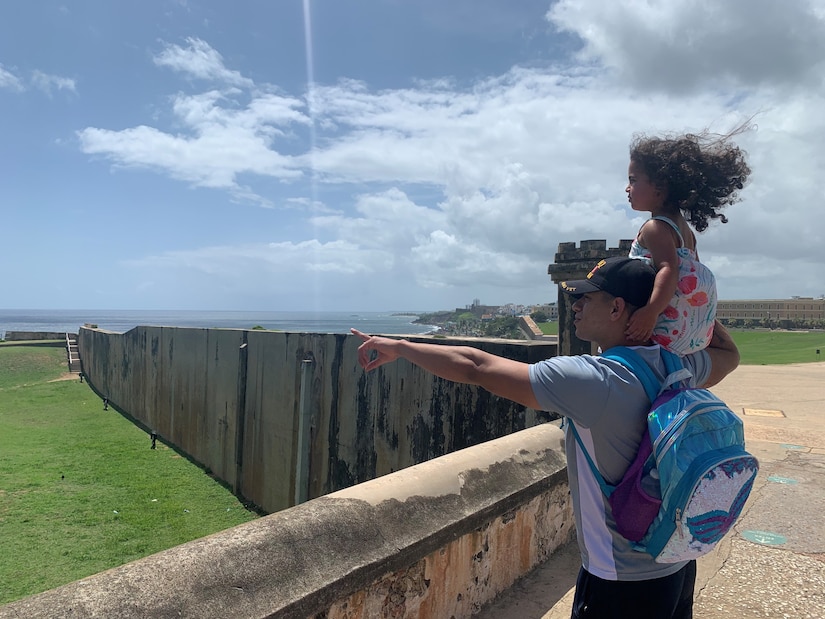 Staff Sgt. Marti holds his daughter Isabella while pointing into the distance in Puerto Rico.