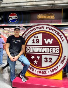 Staff Sgt. Marti stands next to a round Washington football sign.