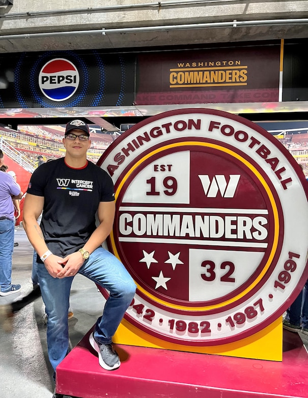 Staff Sgt. Marti stands next to a round Washington football sign.