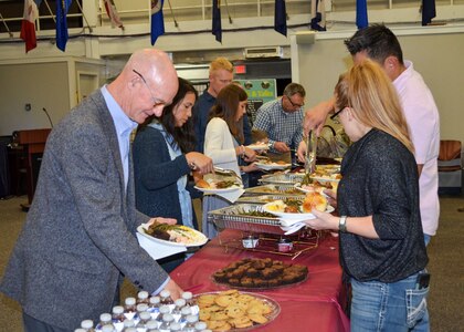 People putting food on their plates in a line.