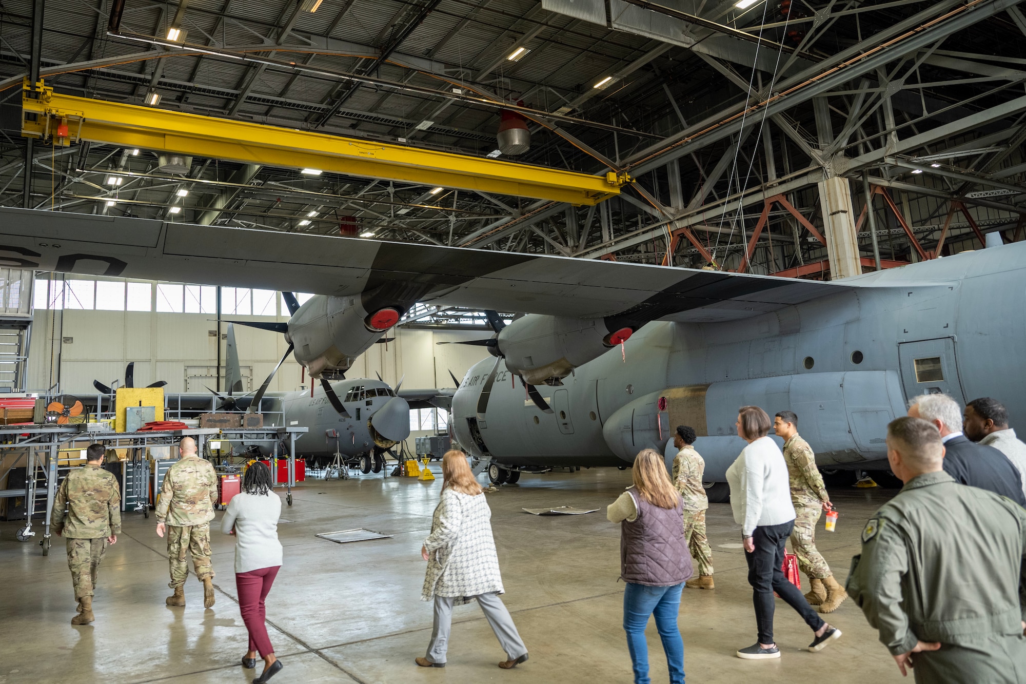 People walk around a C-130 in a group.