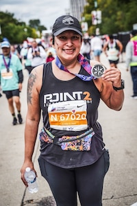 U.S. Air Force Tech. Sgt. Cindy Mascrier, 441st Vehicle Support Chain Operations Squadron program manager, holds a medal after completing a marathon, Oct. 8, 2023, Chicago, Ill. After being diagnosed with thyroid cancer in 2008, Mascrier has beat her illness and is now in remission. She continues to stay resilient while participating in physically demanding activities. (Courtesy photo)
