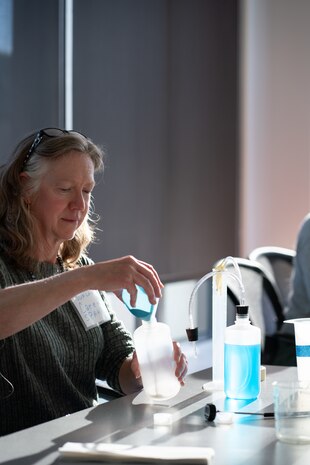 ANNAPOLIS, Md. (Nov. 28, 2023) - Strategic Weapons Facility-Atlantic (SWFLANT) Process Improvement Coordinator Caren Spahr (center) pours yeast in a test bottle during an exercise demonstrating how to make ethanol derived from yeast at a Naval Academy (USNA) Science, Technology, Engineering and Math (STEM) outreach workshop Tuesday, November 28. Nested under Strategic Systems Programs, SWFLANT and Naval Ordnance Test Unit employees attended the day-long workshop--hosted by USNA's STEM Center for Education and Outreach and sponsored by the DoD and the Office of Naval Research--to learn about new and successful tactics, curriculum, and methods for STEM outreach at schools in local communities across the nation. (U.S. Navy Photo by Lt. Jennifer Bowman/Released)