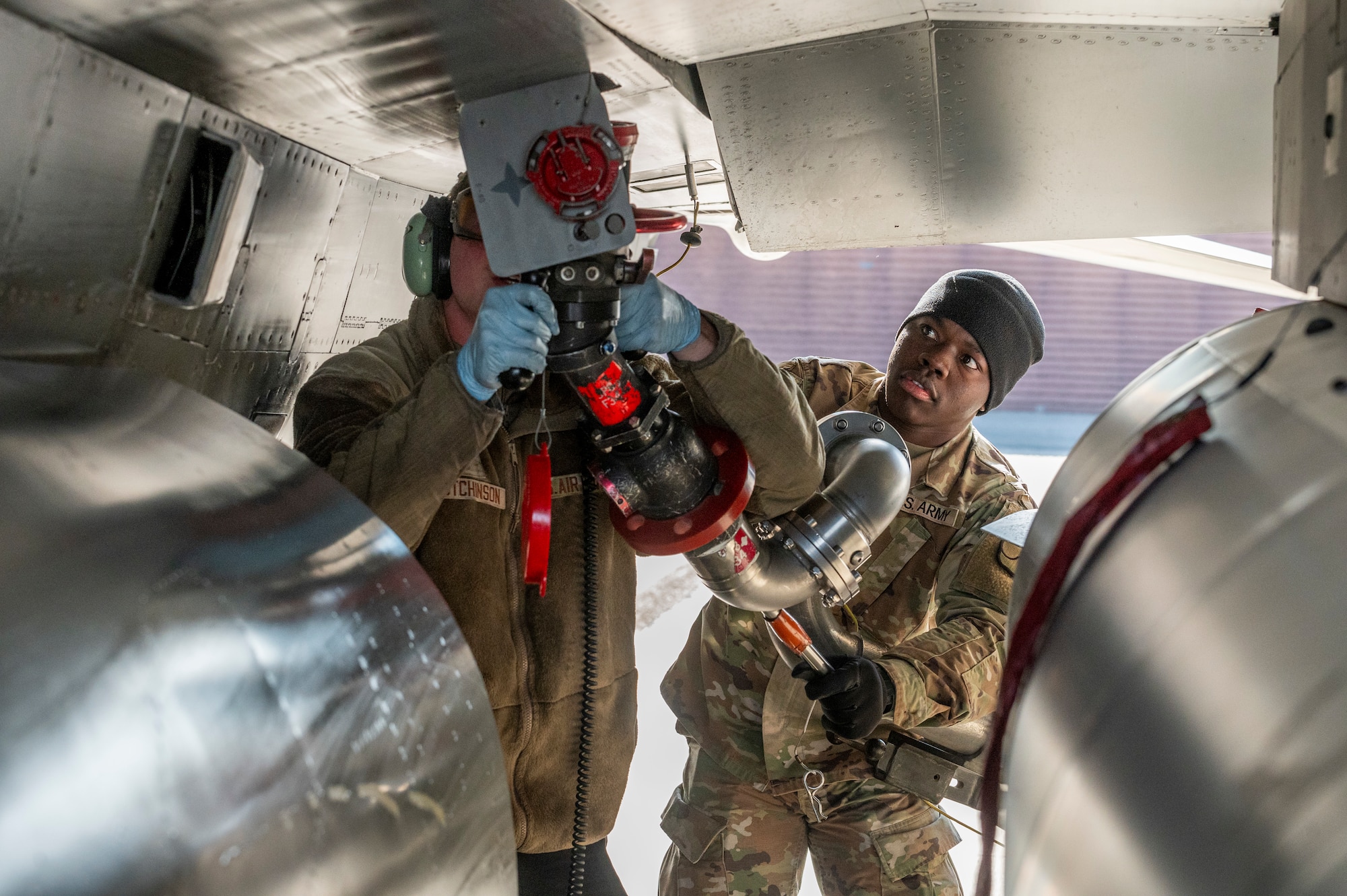 U.S. Air Force Airman 1st Class Clayton Hutchinson, 36th Fighter Generation Squadron crew chief, is assisted by U.S. Army Spc. Komla Amouzou Mlatatwu, 194th Division Support Brigade petroleum supply specialist, while performing a hot-pit refuel during a joint training event at Osan Air Base, Republic of Korea, Nov. 29, 2023.