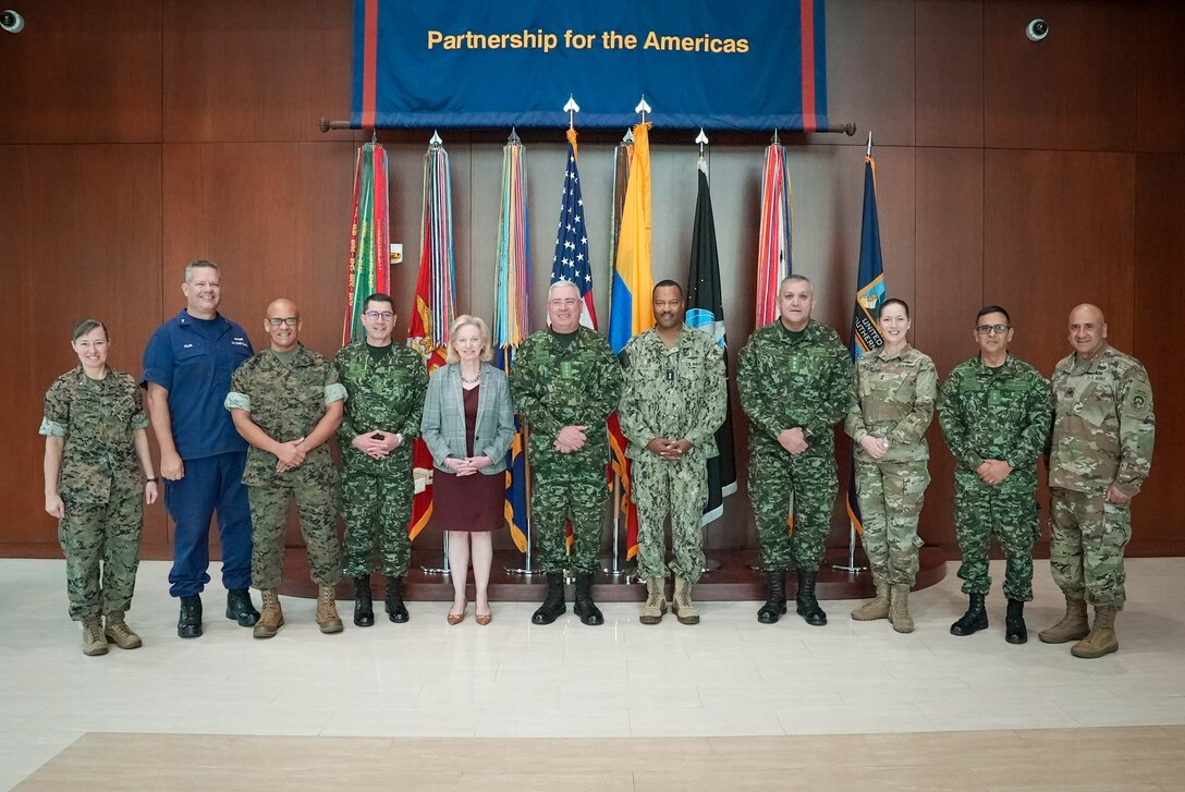 Group photo of military and defense leaders in front of flags.