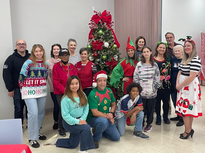 Group photo in festive holiday attire in front of a Christmas tree.
