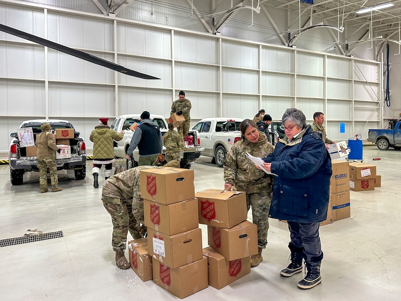Alaska National Guardsmen and Operation Santa Claus volunteers join forces to transfer boxes filled with children’s gifts from a vehicle to a storage pallet at the aviation hangar in Nome, Alaska, Nov. 28, 2023.
