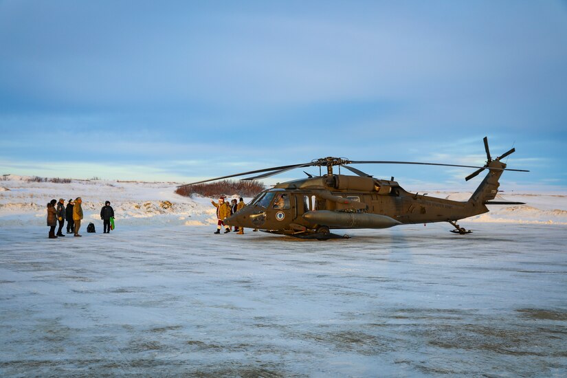 Santa and fellow Operation Santa Claus volunteers greet community members as they exit an Alaska Army National Guard UH-60L Black Hawk near the Inupiat Eskimo village of Golovin, Nov. 30, 2023.