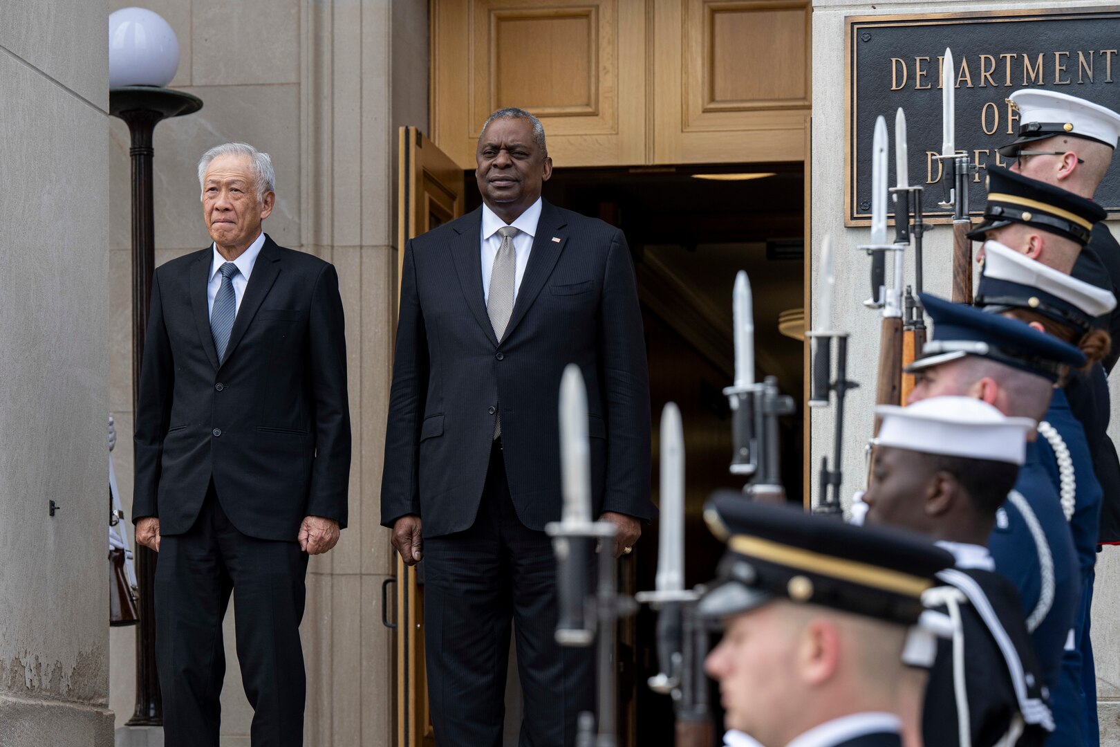Secretary of Defense Lloyd J. Austin III and Singapore Minister for Defence Ng Eng Hen stand on the Pentagon steps during a ceremony.