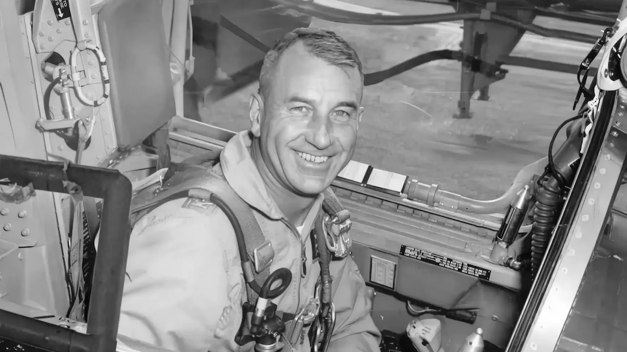 In a black and white image, Air Force Col. Harry Shoup smiles for the camera while seated in an aircraft.