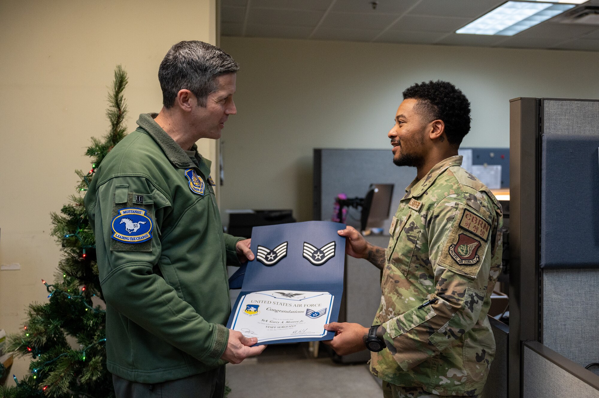 U.S. Air Force Col. William McKibban, left, 51st Fighter Wing commander, awards Staff Sgt. Garry Monroe, 51st Civil Engineer Squadron emergency management journeyman, with a promotion certificate from the Stripes for Exceptional Performers program at Osan Air Base, Republic of Korea, on Dec. 5, 2023. The STEP program is a distinctive promotion initiative that allows commanders to rapidly advance outstanding enlisted members, bypassing standard testing and time requirements. (U.S. Air Force photo by Staff. Sgt. Thomas Sjoberg)