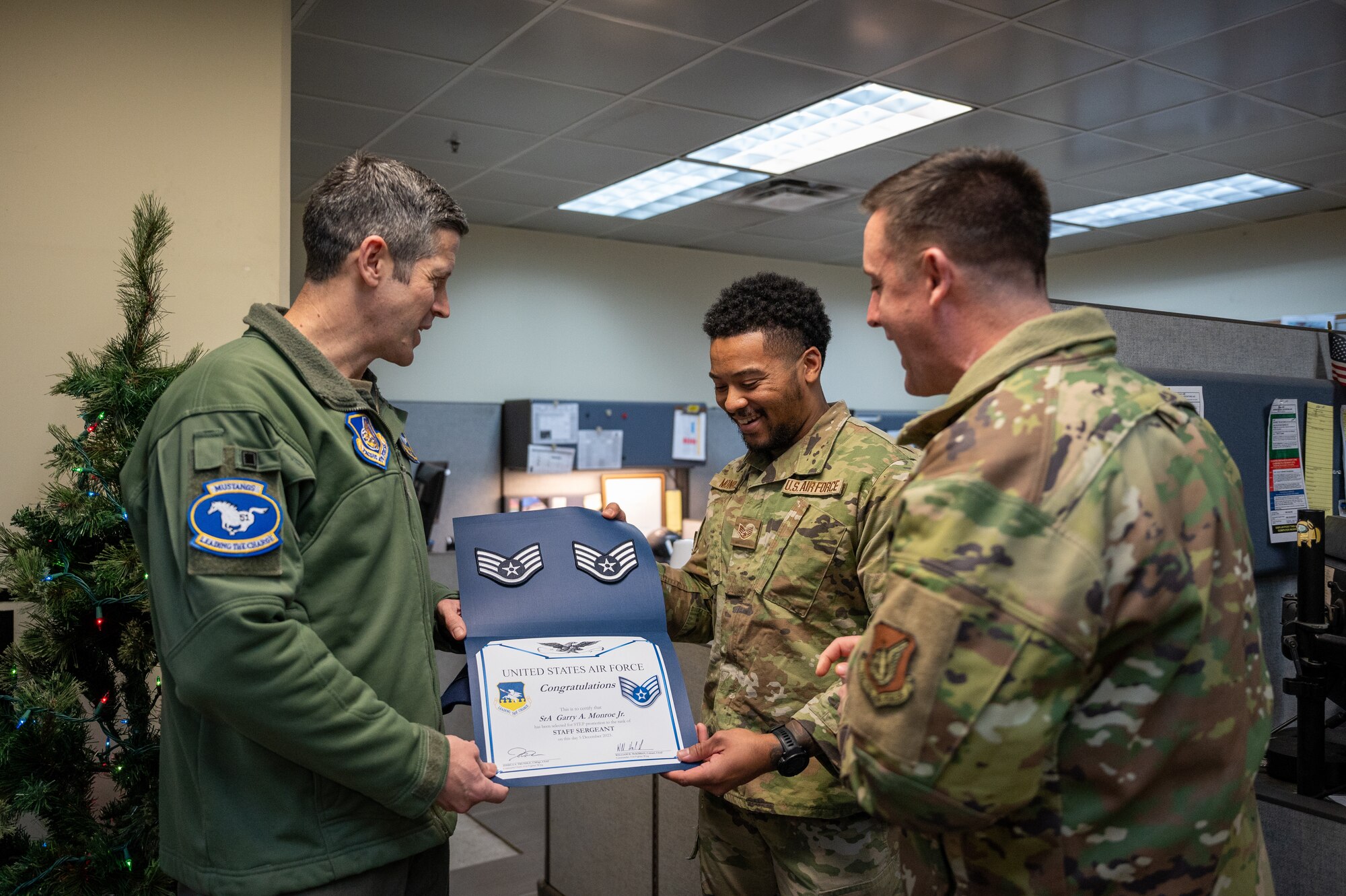 U.S. Air Force Col. William McKibban, left, 51st Fighter Wing commander, and Chief Master Sgt. Joshua Trundle, right, 51st FW command chief, present Staff Sgt. Garry Monroe, 51st Civil Engineer Squadron emergency management journeyman, with a promotion certificate from the Stripes for Exceptional Performers program at Osan Air Base, Republic of Korea, on Dec. 5, 2023. The STEP program is a distinctive promotion initiative that allows commanders to rapidly advance outstanding enlisted members, bypassing standard testing and time requirements. (U.S. Air Force photo by Staff Sgt. Thomas Sjoberg)