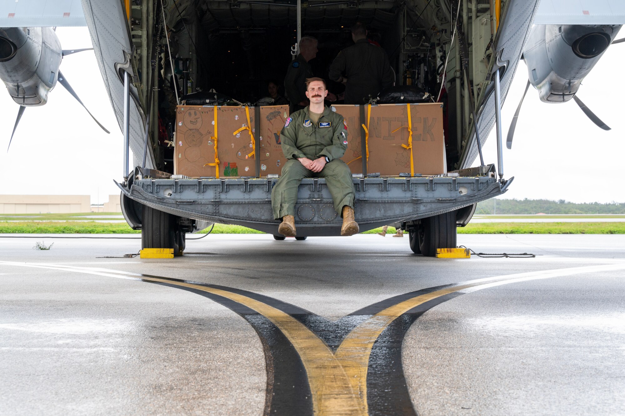 Photo of U.S. Air Force Pilot sitting on the back of a C-130J loaded with bundles for Operation Christmas Drop