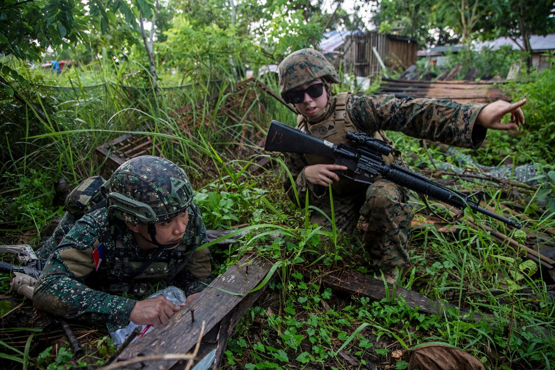 Two Marines conduct a patrol in a jungle.