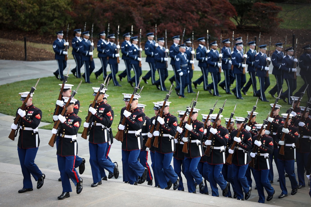 Service members in a line march in formation.