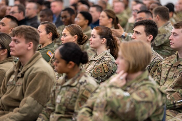 A crowd sits in chairs while listening to people speak.