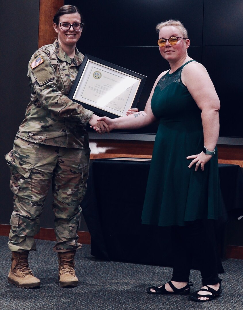 Maj. Alanna Wood presents Letisha Withrow with a Certificate of Appreciation honoring Letisha's "dedication, unwavering support, and selfless commitment as a military spouse" to Staff Sgt. LeAnne Withrow's military career.