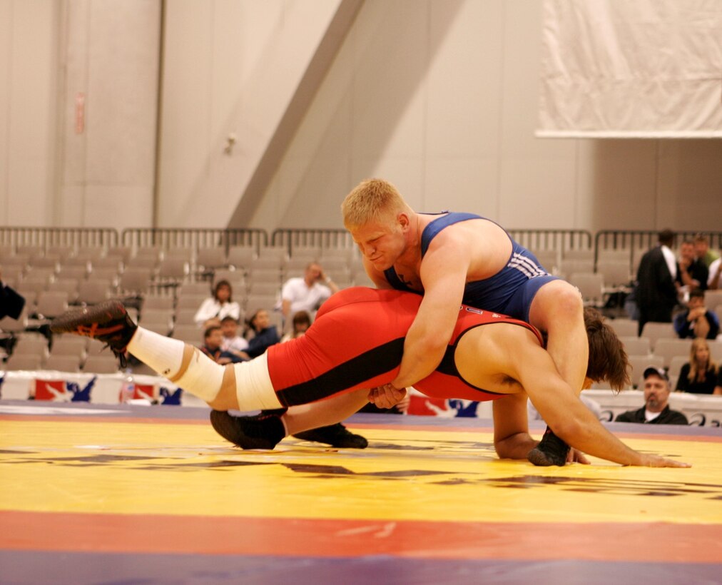 On a knee, AF wrestler grips opponent around the waist while opponent struggles to grab AF wrestler's legs.