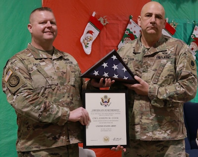 Maj. Alan Davis presents Illinois Army National Guard Chief Warrant Officer 3 Joseph Cook of Lincoln, Illinois, with his retirement certificate and an American Flag at Cook's retirement ceremony.
