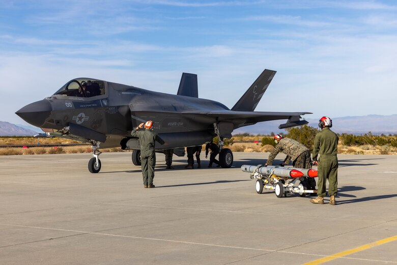 U.S. Marines with the 3rd Marine Aircraft Wing All Type Model Series Armament Team prepare to load ordnance onto an F-35B Lightning II aircraft at a forward arming and refueling point, in support of Exercise Steel Knight 23.2 at Inyokern Airfield, California, Dec. 2, 2023.  ATAT is comprised of aviation ordnance Marines qualified to load and arm every type model series platform in the 3rd MAW fleet. Steel Knight 23.2 is a three-phase exercise designed to train I Marine Expeditionary Force in the planning, deployment and command and control of a joint force against a peer or near-peer adversary combat force and enhance existing live-fire and maneuver capabilities of the Marine Air-Ground Task Force. (U.S. Marine Corps photo by Lance Cpl. Jennifer Sanchez)